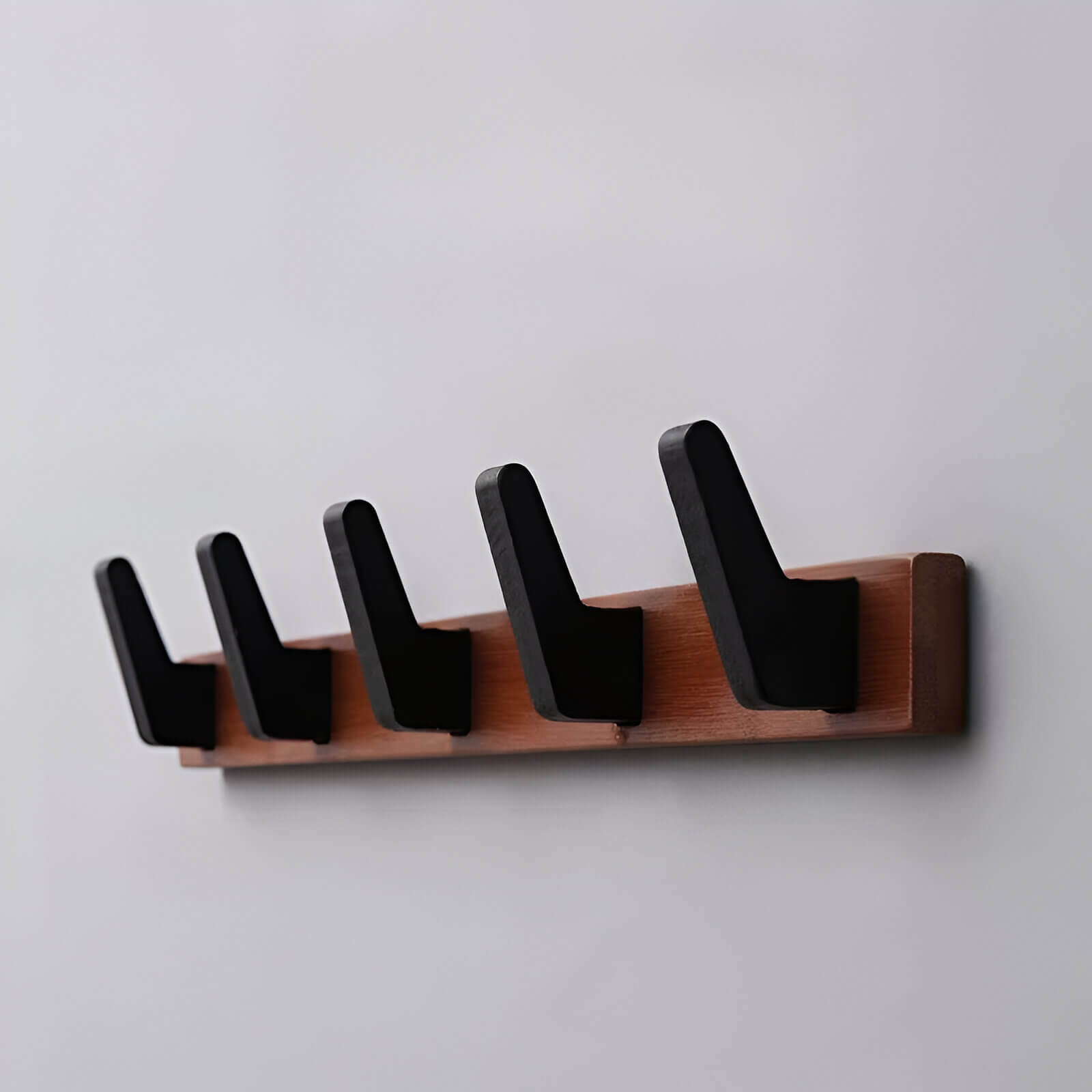 Porte-manteau mural en bois de bambou avec crochets noirs élégants, idéal pour un intérieur moderne et chaleureux